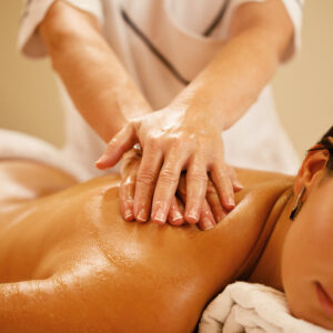 Close-up of woman relaxing during back massage at spa salon.