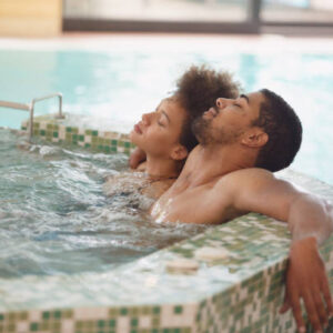 Young couple is having a relaxing bath in a hot tub. They are having a romantic weekend at wellness resort.