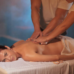 Two Massage Therapist doing healing massage, Massage in four hands.  Woman enjoying in relaxing massaging at health spa treatment.