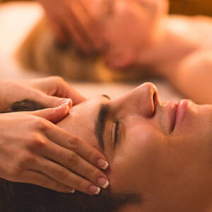 Couple at the spa. Focus is on foreground, on young man receiving head massage.