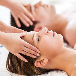 Young couple at spa receiving head massage. Focus is on foreground.
