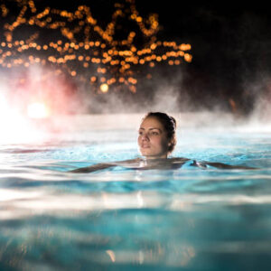 Young woman enjoying in a heated swimming pool at night.