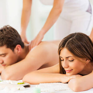 Young couple relaxing at the spa while receiving back massage. Focus is smiling woman.