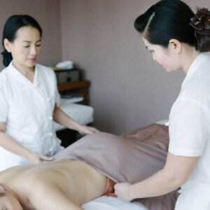 Therapists preparing customer for four-hands aromatherapy oil massage