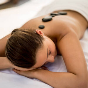 Beautiful woman relaxing at the spa with a hot stone massage - wellness concepts