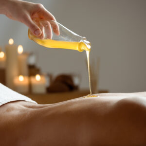 Honey pouring on girl's naked back in spa salon. Copy space.