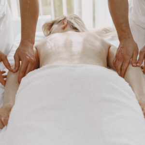 The massage with four hands. Concept of healthcare and female beauty. Two masseuses make a double  massage of a girl. Woman in a spa salon.