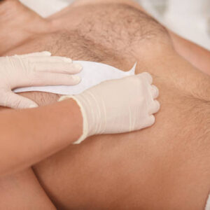 Cosmetologist doing waxing on torso of unrecognizable male client