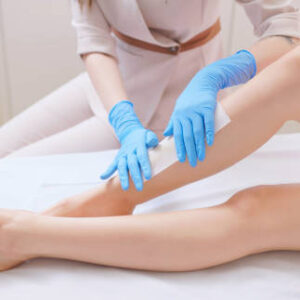 side view closeup asian female beautician is applying wax to remove woman customer calf hair in medical beauty clinic - beauty treatment procedures for skin and health care concept
