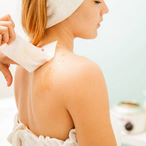 Closeup of a woman's back covered with honey wax and a therapist removing her hair with a strip at a spa